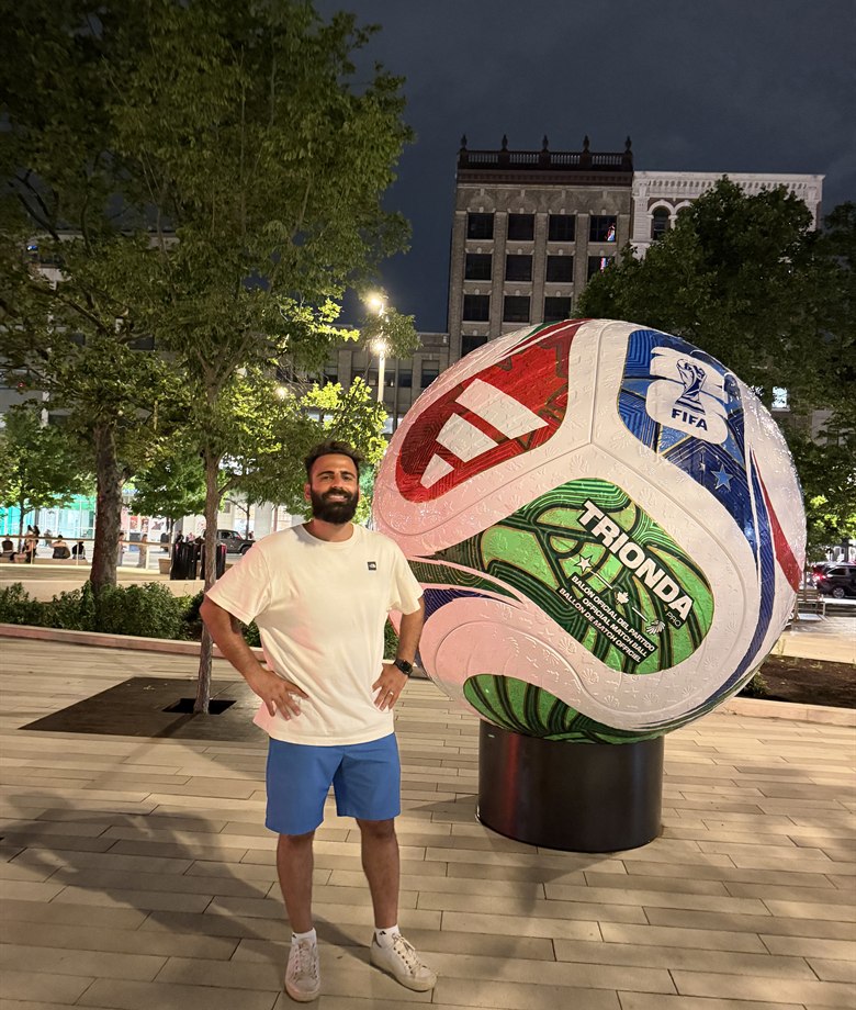 Mushtaq Alzuhairi standing beside a large World Cup soccer ball installation